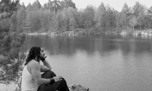 Young Man sitting alone outdoor Travel Lifestyle concept with lake. Black and white. - Photo, Image