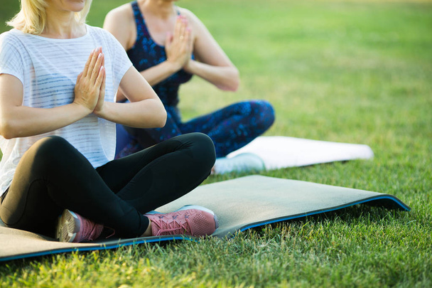 two adult women aged yoga outdoors in summer in the park - Valokuva, kuva