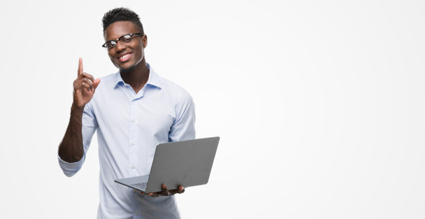 幸せそうな顔、ナンバーワンのアイデアや質問ポインティング指で驚いてラップトップ コンピューターを使用して若いアフリカ系アメリカ人のビジネスマン - 写真・画像