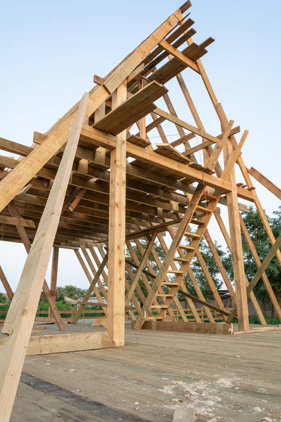 日没、Shagany ラグーン、ウクライナで建設中の家に木製フレームの組み立てのメンバーの低角度表示. - 写真・画像