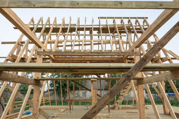 Sparren des Rahmens eines Holzhauses bei Sonnenuntergang. Bau eines Fachwerkhauses in der Ukraine. - Foto, Bild