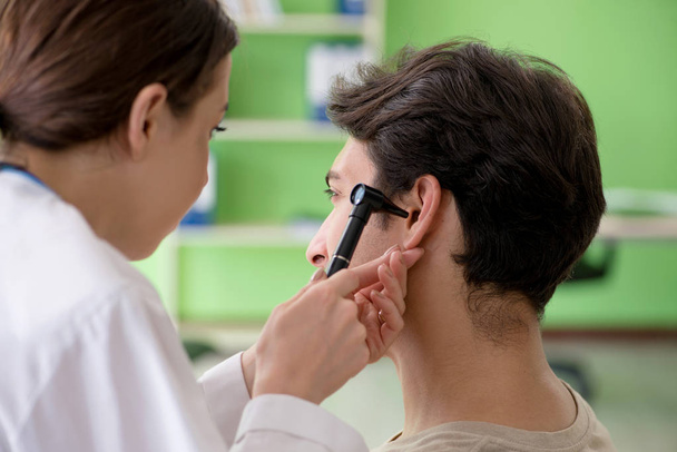 Γυναίκα γιατρός ελέγχει τους ασθενείς αυτί κατά τη διάρκεια της ιατρικής εξέτασης  - Φωτογραφία, εικόνα