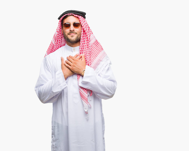 Young handsome man wearing keffiyeh over isolated background smiling with hands on chest with closed eyes and grateful gesture on face. Health concept. - Photo, Image
