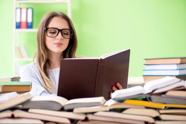 Jonge vrouwelijke student bereidt zich voor op examens met veel boeken  - Foto, afbeelding