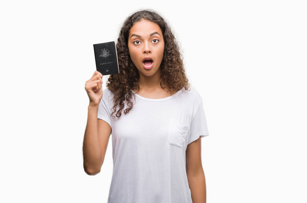 Giovane donna ispanica in possesso di passaporto dell'Australia spaventata in stato di shock con una faccia a sorpresa, spaventata ed eccitata con espressione di paura
 - Foto, immagini