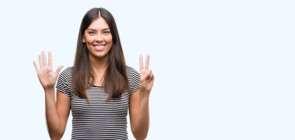 Giovane bella donna ispanica mostrando e indicando con le dita il numero sette sorridendo fiducioso e felice
. - Foto, immagini
