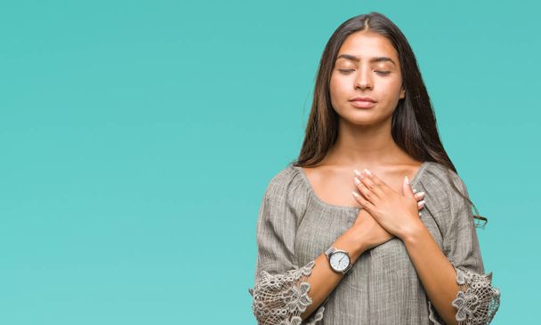 Young beautiful arab woman over isolated background smiling with hands on chest with closed eyes and grateful gesture on face. Health concept. - Photo, Image