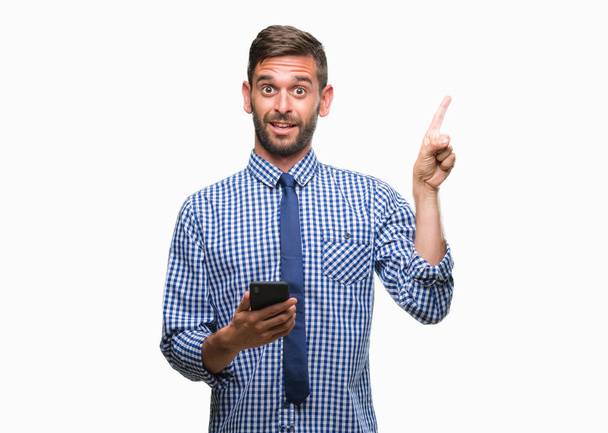 Fiatal hadsome ember SMS üzenetet használ smartphone felső elszigetelt háttér nagyon boldog, mutat, a kéz és az ujjak az oldalon - Fotó, kép
