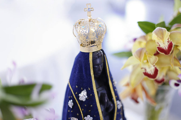 Statue de l'image de Notre-Dame d'Aparecida, mère de Dieu dans la religion catholique, patronne du Brésil, décorée de fleurs et d'orchidées
 - Photo, image