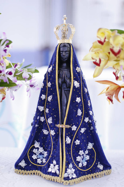 Socha z obrazu Panny Marie Aparecida, Matka Boží v katolické náboženství, patronka Brazílie, zdobené květinami a orchideje - Fotografie, Obrázek