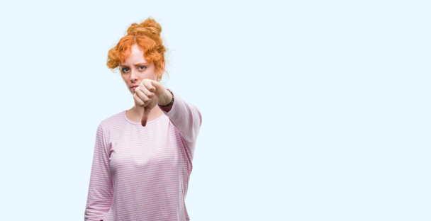 Fiatal vöröshajú nő keresi a boldogtalan és dühös mutatja elutasítása, és negatív, a hüvelykujj le gesztus. Rossz kifejezés. - Fotó, kép