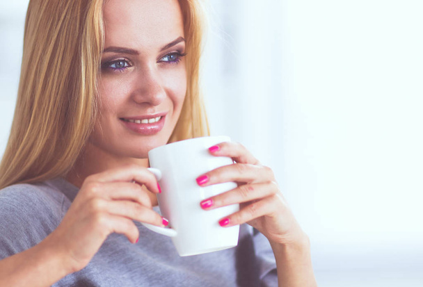 Young beautiful woman with a cup on sofa at home - Photo, image