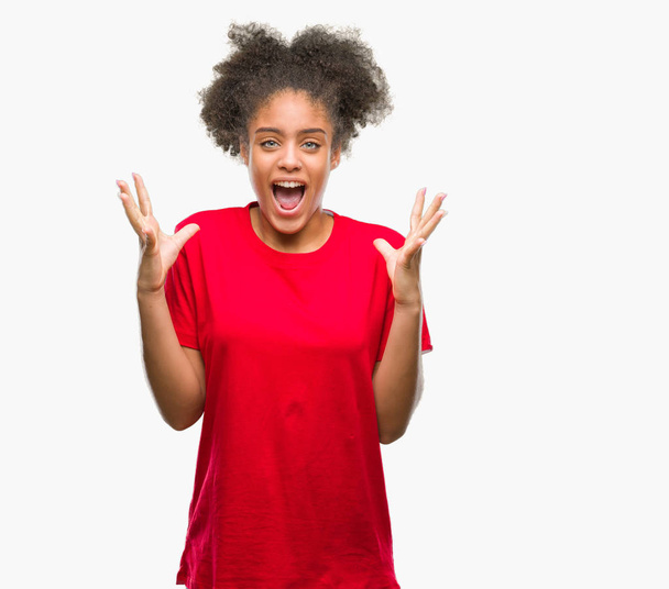 Jeune femme afro-américaine sur fond isolé célébrant fou et étonné pour le succès avec les bras levés et les yeux ouverts hurlant excités. Concept gagnant
 - Photo, image