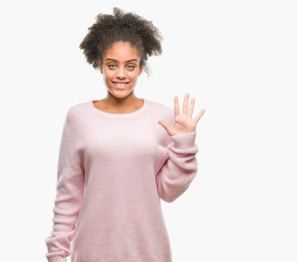 Mladá Američanka afro nosit zimní svetr izolované pozadí zobrazení a ukázal prsty číslo pět, zatímco s úsměvem a spokojené. - Fotografie, Obrázek