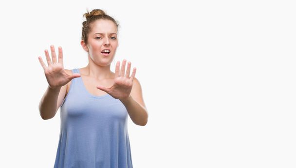 Young blonde woman afraid and terrified with fear expression stop gesture with hands, shouting in shock. Panic concept. - Photo, Image