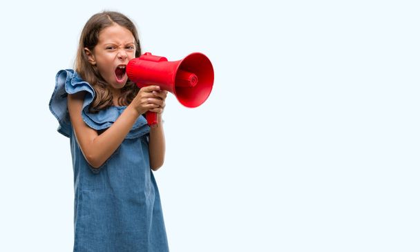 Brunetka dziewczynka hiszpanin gospodarstwa czerwony megafon zirytowany i sfrustrowany, krzycząc z gniewem, szalony i wrzask ręce, koncepcja gniew - Zdjęcie, obraz