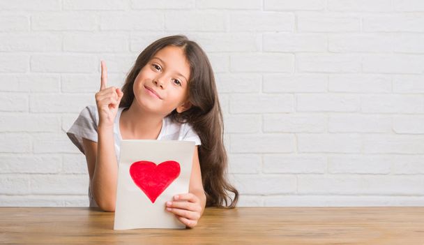 Tablo veren anne günü kartı üzerinde oturan genç İspanyol çocuğun bir fikirle sürpriz veya işaret parmağı ile mutlu yüz soru, number one - Fotoğraf, Görsel