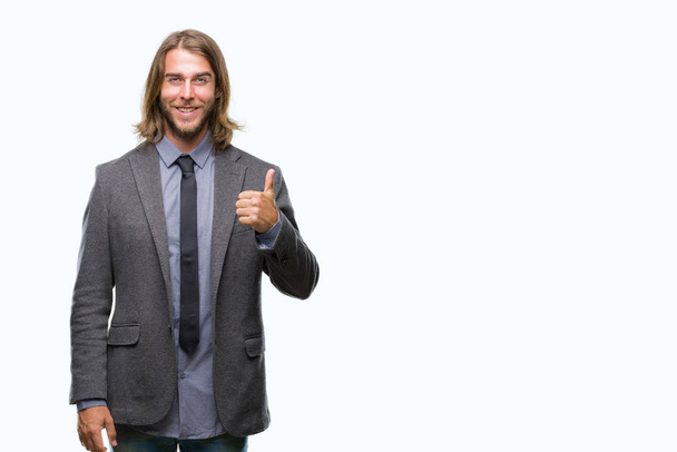 Young handsome business man with long hair over isolated background doing happy thumbs up gesture with hand. Approving expression looking at the camera with showing success. - Photo, image