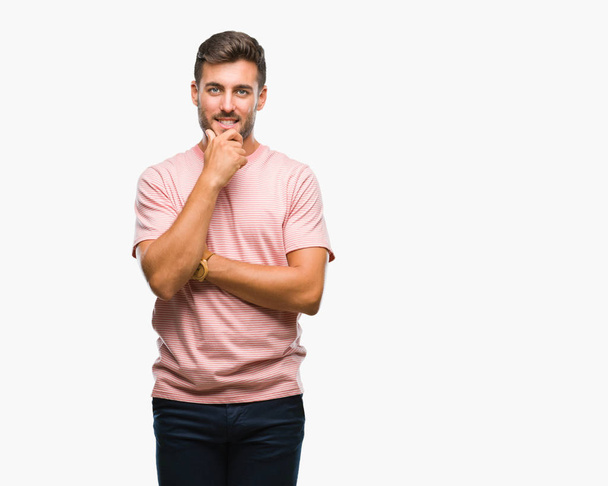 Young handsome man over isolated background looking confident at the camera with smile with crossed arms and hand raised on chin. Thinking positive. - Photo, Image