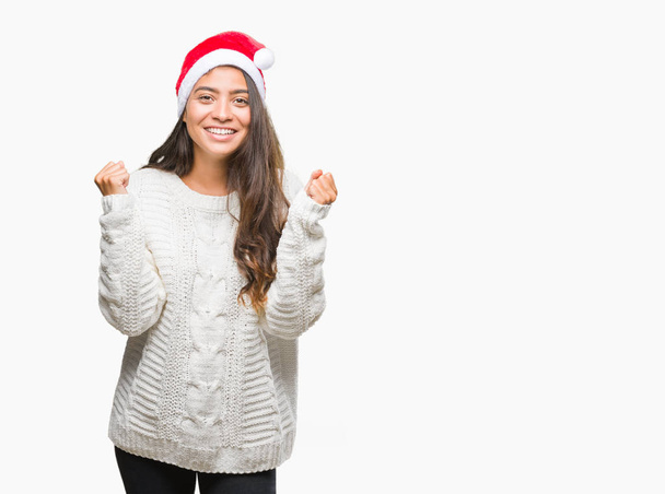 Αραβικά γυναίκα φοράει καπέλο Χριστουγέννων πάνω από απομονωμένες φόντο γιορτάζει έκπληκτος και κατάπληκτος για την επιτυχία με τα χέρια υψωμένα και ανοίξτε τα μάτια. Νικητής έννοια. - Φωτογραφία, εικόνα