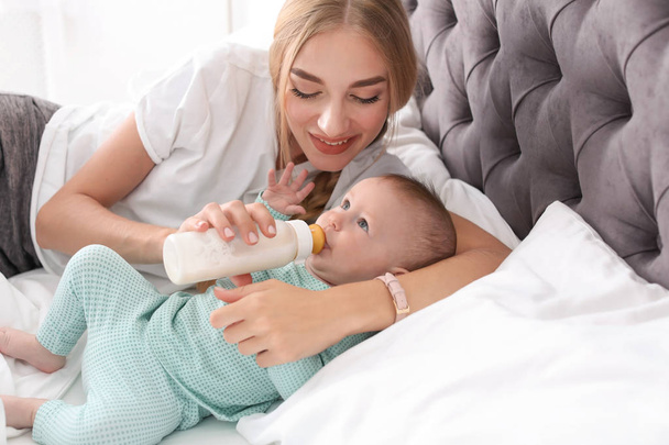 Женщина кормит своего ребенка в спальне. Здоровое детское питание
 - Фото, изображение