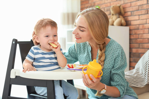 Woman feeding her child in highchair at home. Healthy baby food - Foto, Imagem