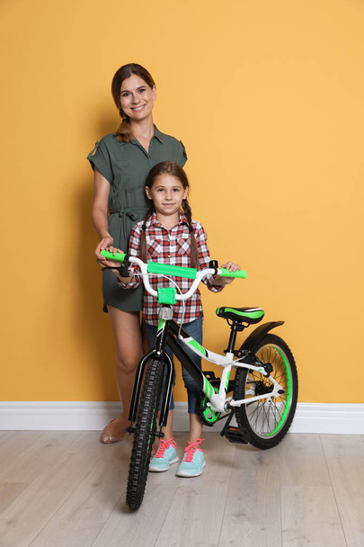Portrait of parents and their daughter with bicycle near color wall - Photo, Image