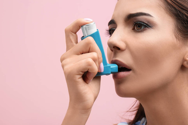 Young woman using asthma inhaler on white background, closeup - Foto, imagen