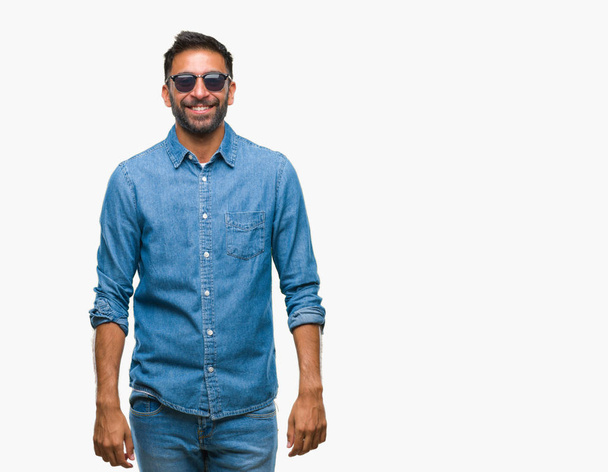 Дорослий іспаномовний чоловік носить сонцезахисні окуляри над ізольованим тлом з щасливою і холодною посмішкою на обличчі. Щаслива людина
. - Фото, зображення