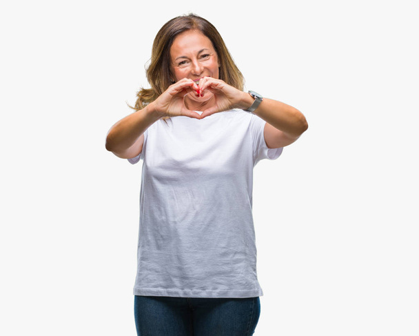 Femme hispanique âgée du Moyen Âge sur fond isolé souriant dans l'amour montrant le symbole du cœur et la forme avec les mains. Concept romantique
. - Photo, image