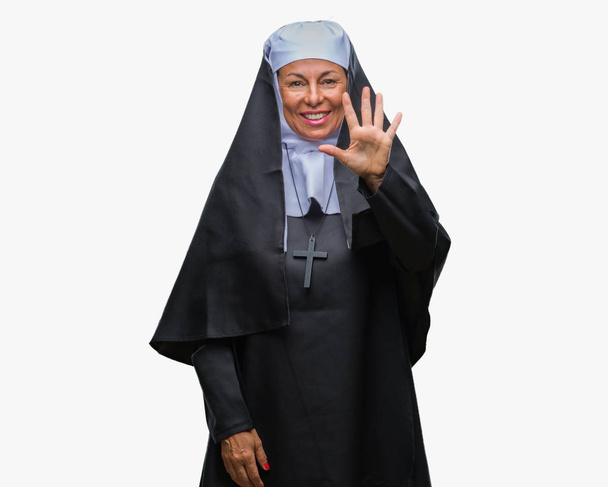 A középkorú idősebb keresztény katolikus apáca nő felett elszigetelt háttér bemutatás és ujjal felfelé mutató szám öt, miközben mosolyogva, magabiztos és boldog. - Fotó, kép