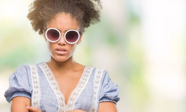 Jeune femme afro-américaine portant des lunettes sur fond isolé sceptique et nerveux, désapprouvant l'expression sur le visage avec les bras croisés. Personne négative
. - Photo, image