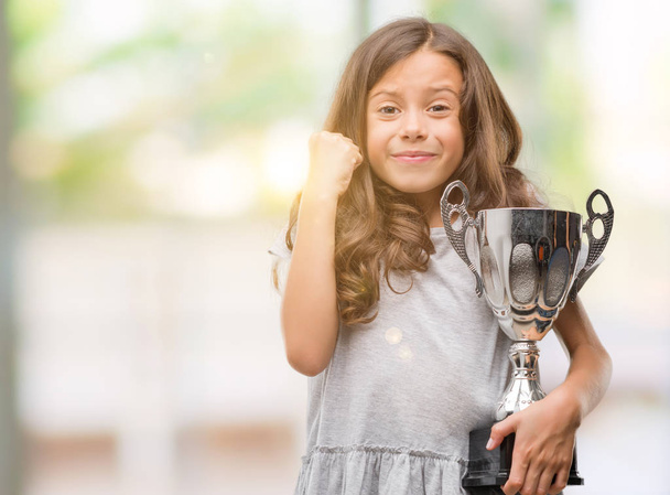 Bruna ragazza ispanica in possesso di un trofeo urlando orgoglioso e celebrando la vittoria e il successo molto eccitato, esultante emozione
 - Foto, immagini
