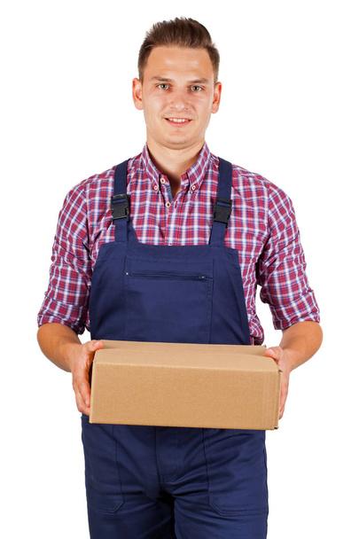 Trabalhador bonito no pacote de entrega uniforme em uma caixa de papelão - em isolado
 - Foto, Imagem