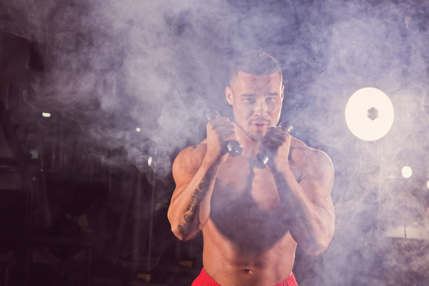 Mocny człowiek robi ćwiczenia bokserskie, dzięki czemu bezpośrednie trafienie z hantlami. Fotografia sportowa mięśni mężczyzna. Siłę i motywację - Zdjęcie, obraz