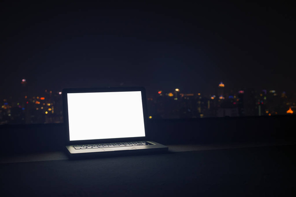 Κενό οθόνη φορητού υπολογιστή με cityscape τη νύχτα, έννοια διάλειμμα εργασίας. - Φωτογραφία, εικόνα