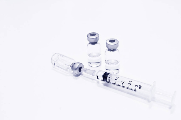 Flacon van Drug of vaccin en 3 ml Plastic injectiespuit met naald geïsoleerd op de witte achtergrond, blauwe tone kleur - Foto, afbeelding