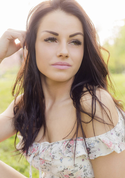 Προσωπογραφία γυναίκας με όμορφο μακιγιάζ φοράει καλοκαίρι φόρεμα κάθεται εξωτερική  - Φωτογραφία, εικόνα