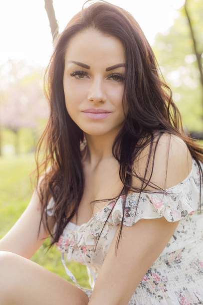 Προσωπογραφία γυναίκας με όμορφο μακιγιάζ φοράει καλοκαίρι φόρεμα κάθεται εξωτερική  - Φωτογραφία, εικόνα