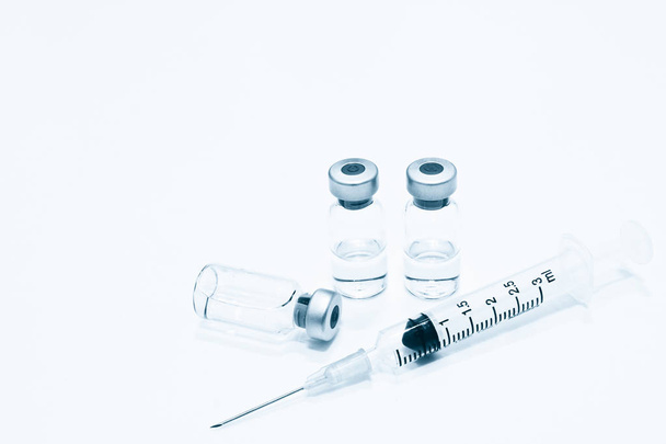 Flacon van Drug of vaccin en 3 ml Plastic injectiespuit met naald geïsoleerd op de witte achtergrond, blauwe tone kleur - Foto, afbeelding