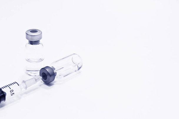 Vial de medicamento o vacuna y jeringa de plástico de 3 ml con aguja aislada sobre el fondo blanco, color azul
 - Foto, Imagen