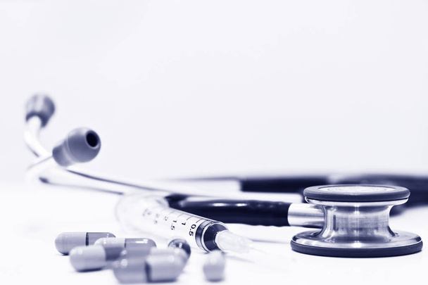 Stetoskooppi, lääkekapseli ja 3 ml:n muoviruisku neulalla Eristettynä valkoisella pohjalla
 - Valokuva, kuva