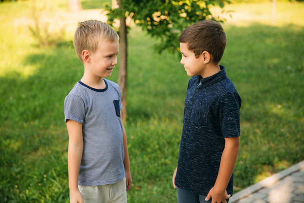 Δύο παιδιά παίζουν στο πάρκο. Δύο όμορφα αγόρια σε μπλουζάκια και Σορτσάκια να διασκεδάσουν. Αυτοί χαμογελαστός - Φωτογραφία, εικόνα