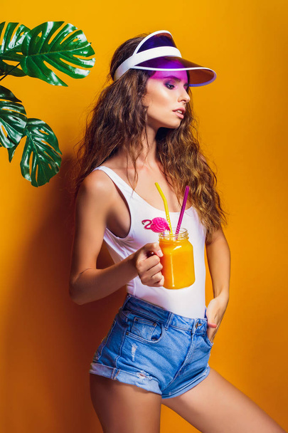 Sexy Woman in white swimsuit and blue jeans shorts, trendy visor holding beverage - Foto, immagini