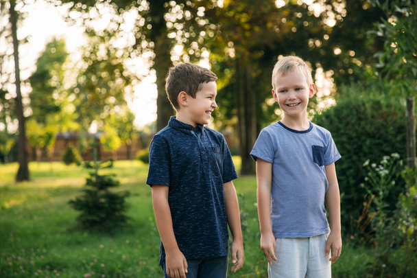 Двоє дітей хлопчиків друзі ходять в парку в сонячний літній день
 - Фото, зображення