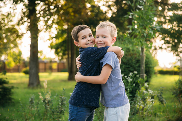 Twee kinderen jongens vrienden wandelen in het park op een zonnige zomerdag - Foto, afbeelding