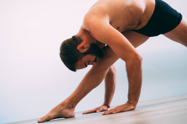 Yoga. Young man doing yoga exercise isolated on a white background. Yogi master workout on white urban studio. Yoga lifestyle healthy concept. - Фото, изображение