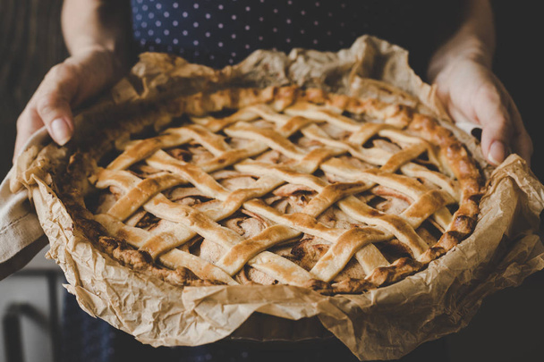 Hands holding homemade delicious apple pie. Close up. - Фото, изображение