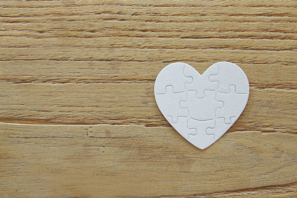 Top view image of paper white heart puzzle over wooden table. Health care, donate, world heart day and world health day concept - Photo, image