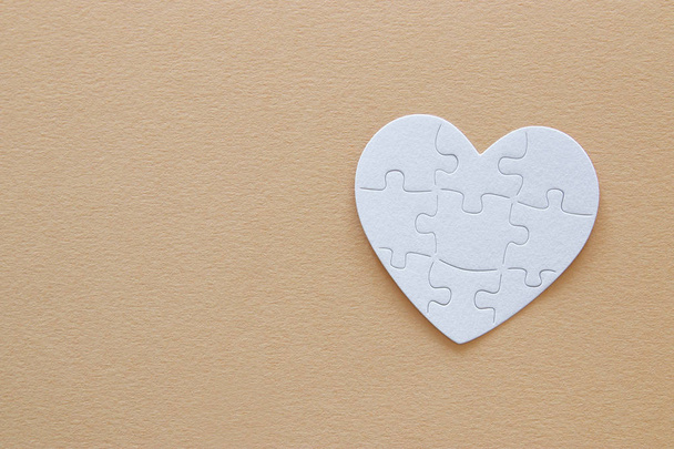 Top view image of paper white heart puzzle over brown pastel background. Health care, donate, world heart day and world health day concept - Foto, immagini